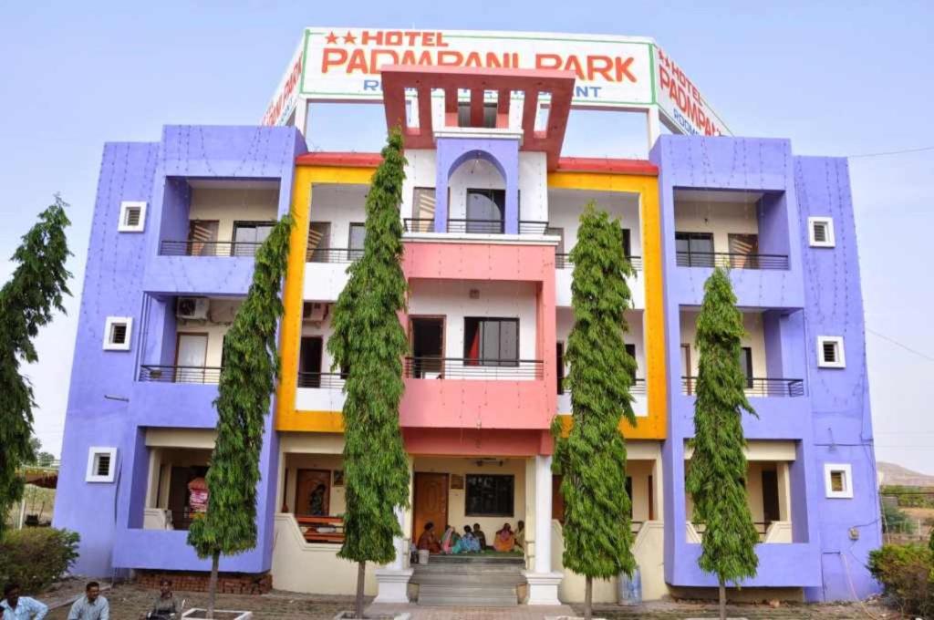 ein farbenfrohes Gebäude mit Bäumen davor in der Unterkunft Hotel Padmapani Park Fardapur in Phardāpur