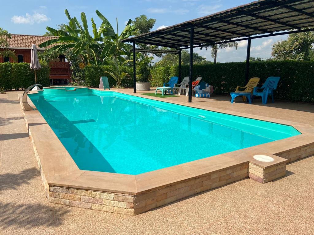 a swimming pool in a yard with chairs and a pavilion at Lampang Hideaway Guesthouse in Lampang