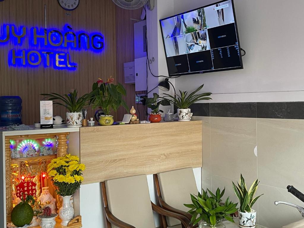 Huy Hoàng Hotel في فان ثيت: غرفة مع طاولة مع الزهور وتلفزيون
