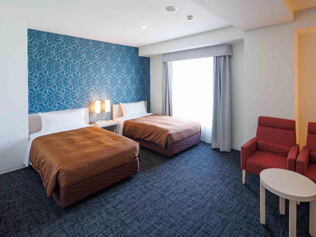 a hotel room with two beds and a red chair at J - HOTEL RINKU - Vacation STAY 42902v in Tokoname