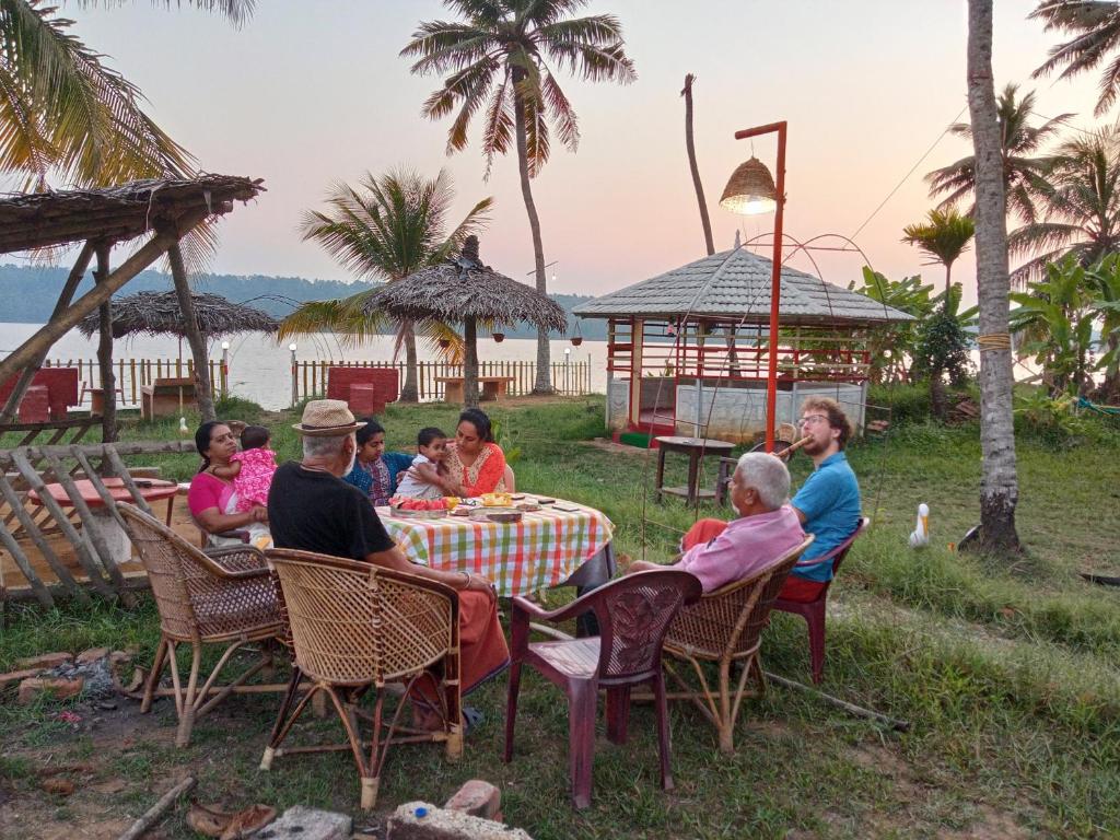 a group of people sitting at a table on the beach at Lake Homes in Varkala