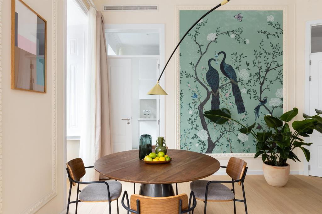 A round dining or work table set against a large botanical mural in a bright apartment room.