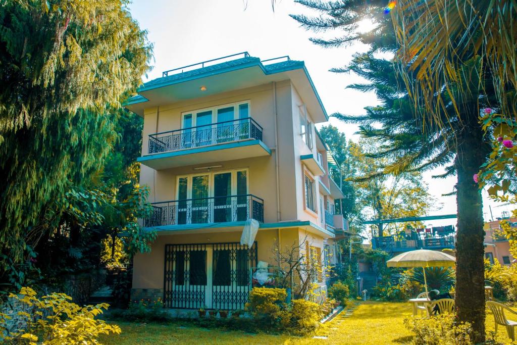 a tall yellow building with a balcony and trees at Holiday Home near Swayambhunath Stupa in Kathmandu