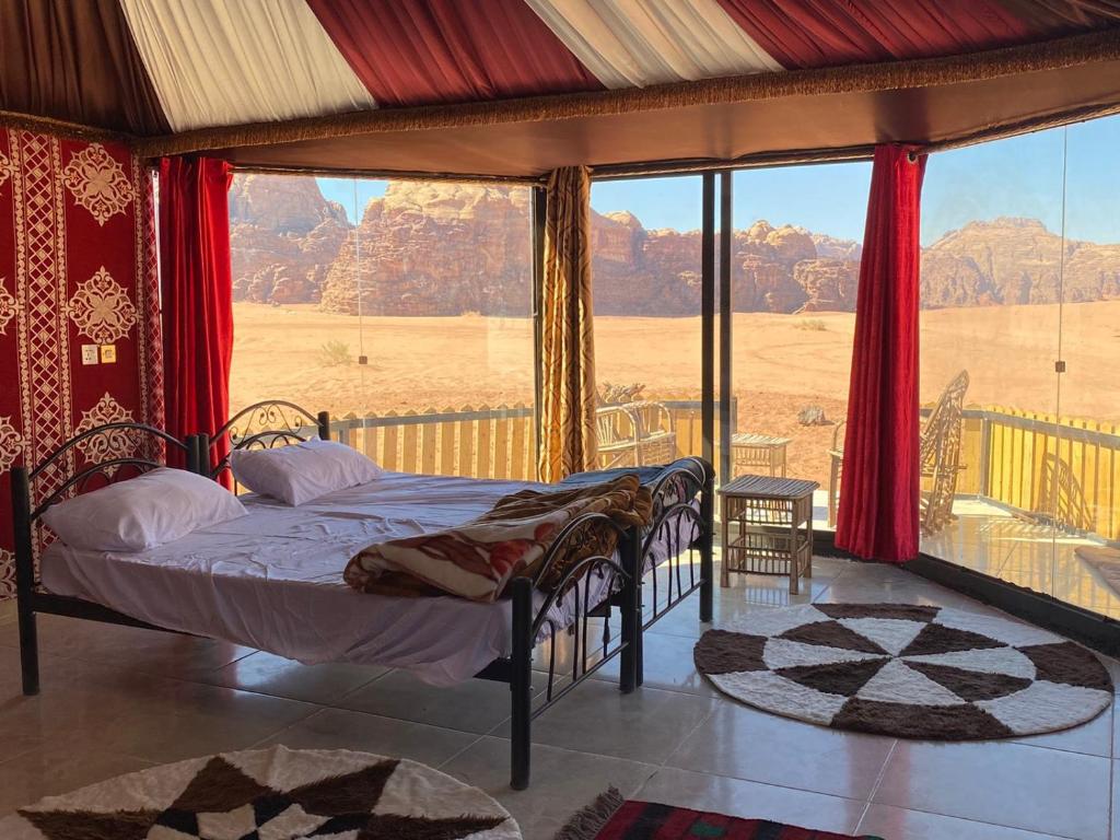 una camera da letto con un letto e una grande finestra di Bedouin Tours Camp a Wadi Rum