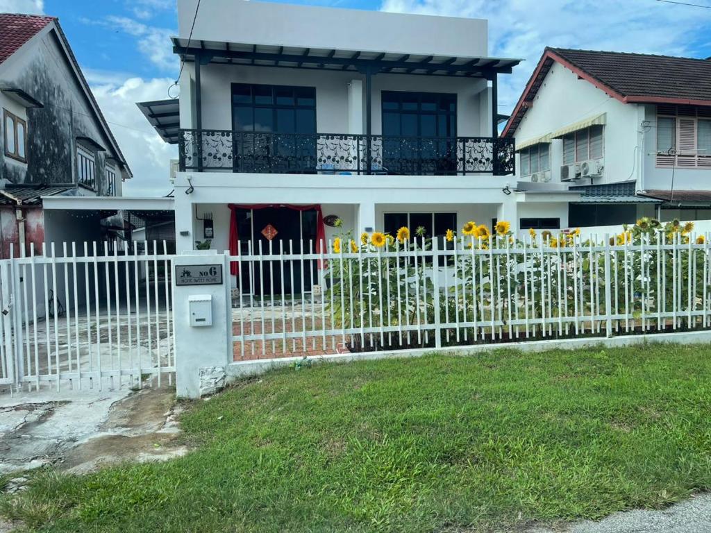 une clôture blanche devant une maison ornée de fleurs jaunes dans l'établissement VegeGarden Cozy Home @Ipoh Town Center, à Ipoh