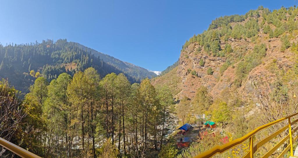 a view of a mountain with trees and an umbrella at Alooma House in Vashisht