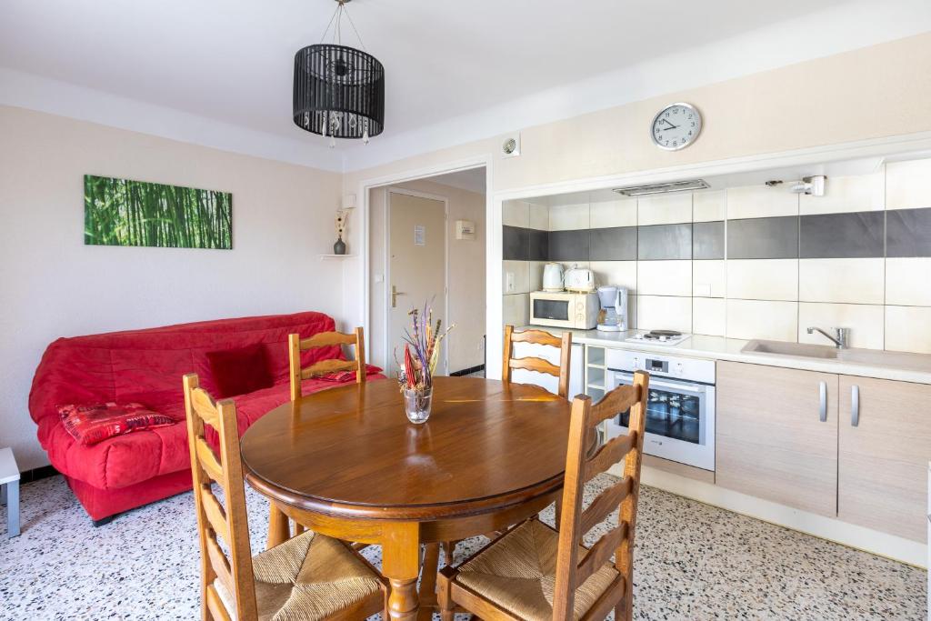 eine Küche und ein Esszimmer mit einem Tisch und einem roten Sofa in der Unterkunft Pamplemousse - Appt à 10min d'Argelès-Sur-Mer in Saint-André