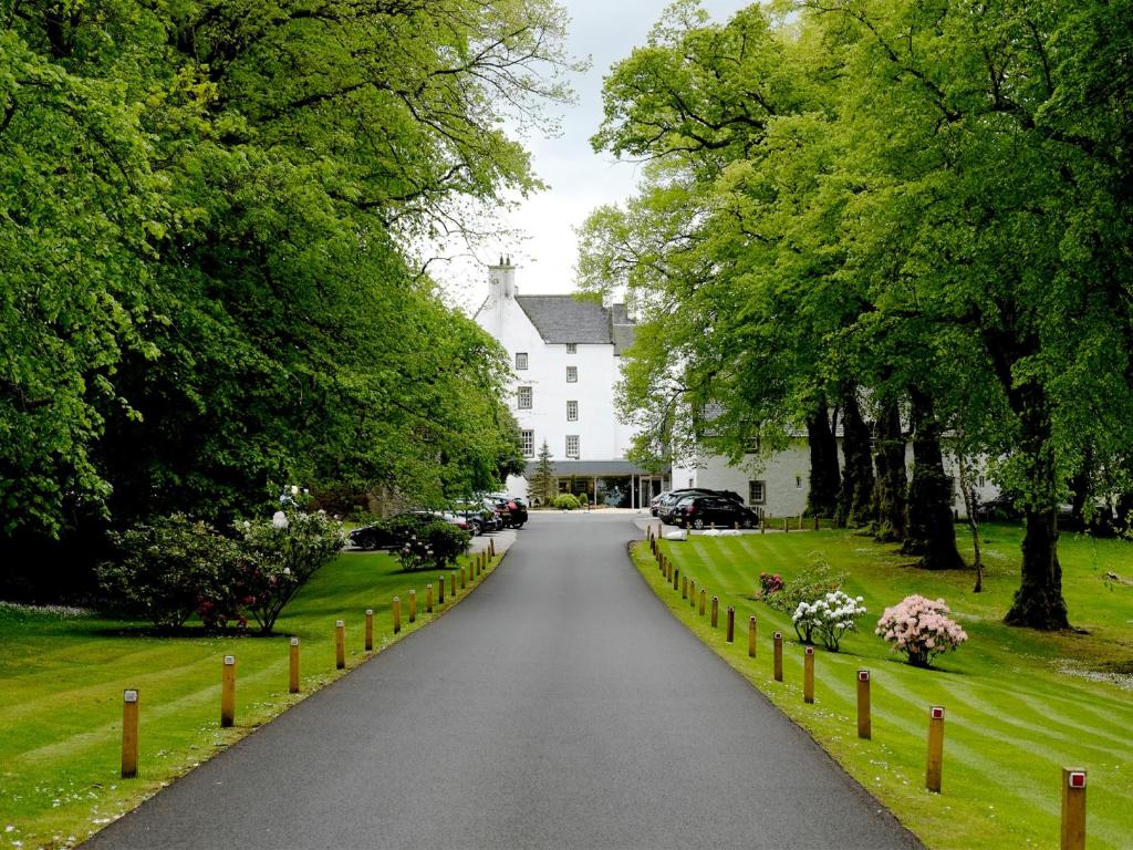 a road in front of a white house with trees at Macdonald Houstoun House in Livingston
