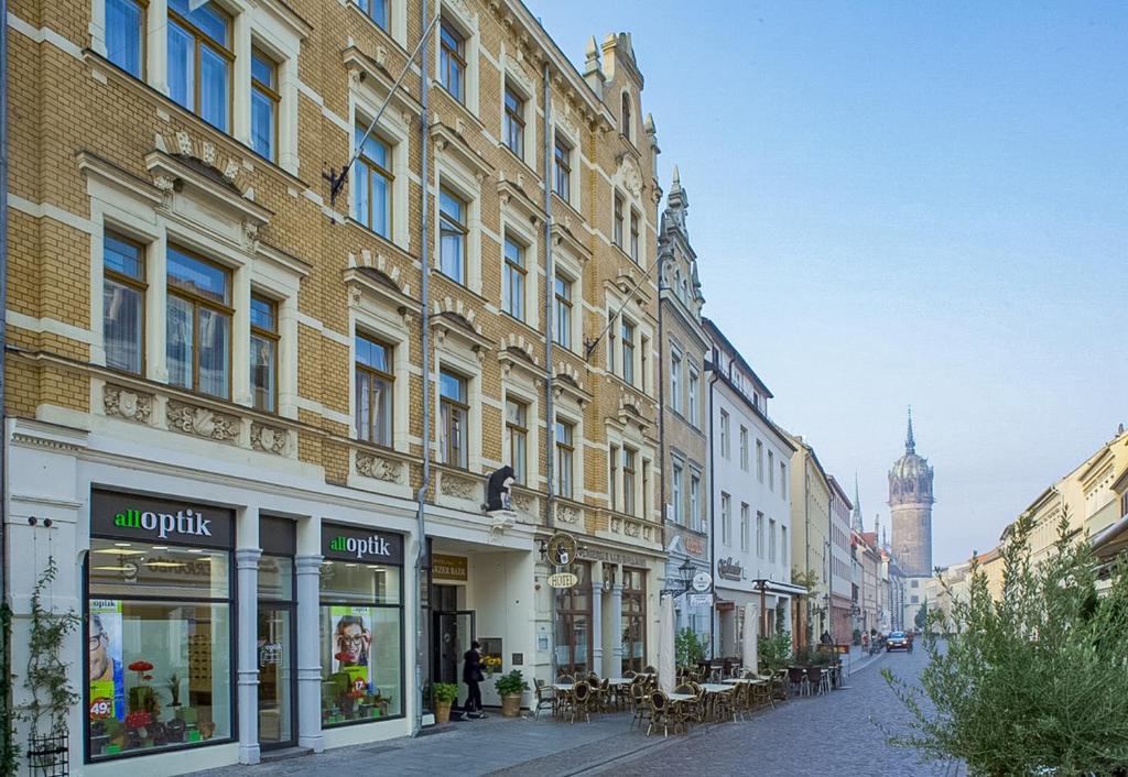 uma rua da cidade com edifícios e mesas e cadeiras em Boutique Hotel Schwarzer Baer em Wittenberg