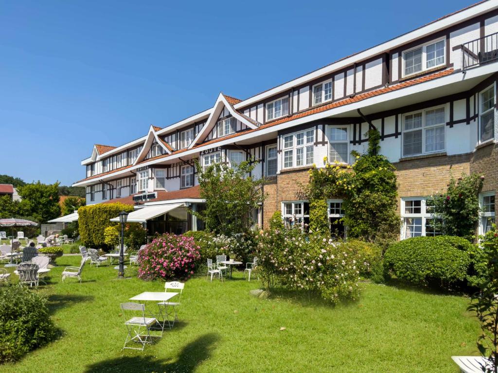 ein großes Gebäude mit einem Hof mit Tischen und Stühlen in der Unterkunft Hotel Pavillon Du Zoute in Knokke-Heist