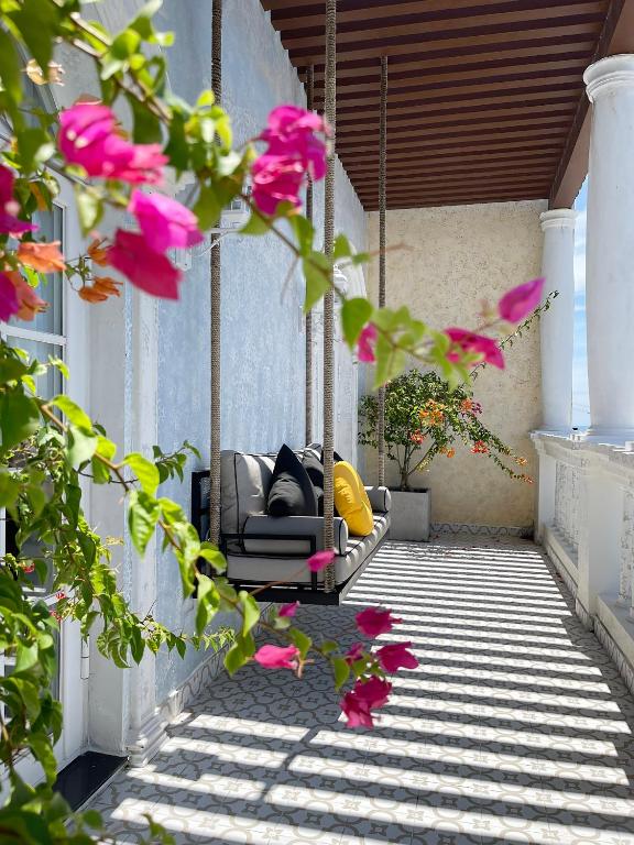 a swing on a porch with pink flowers at Le Bonheur Hotel in Phú Quốc