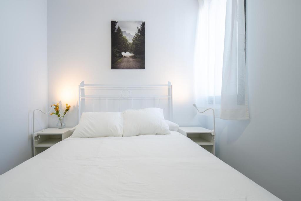 a white bedroom with a white bed and two tables at Conjunto de APARTAMENTOS ANTIGUO PALACIO HOTEL PARIS in Huelva