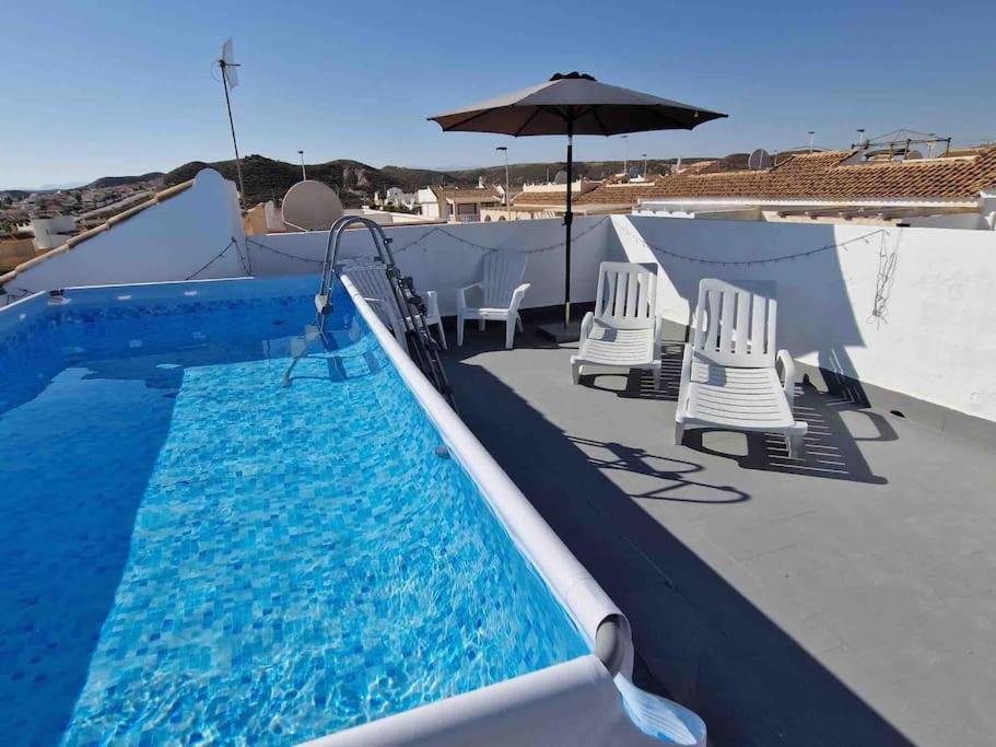 a swimming pool with chairs and an umbrella at Villa Rose in Camposol