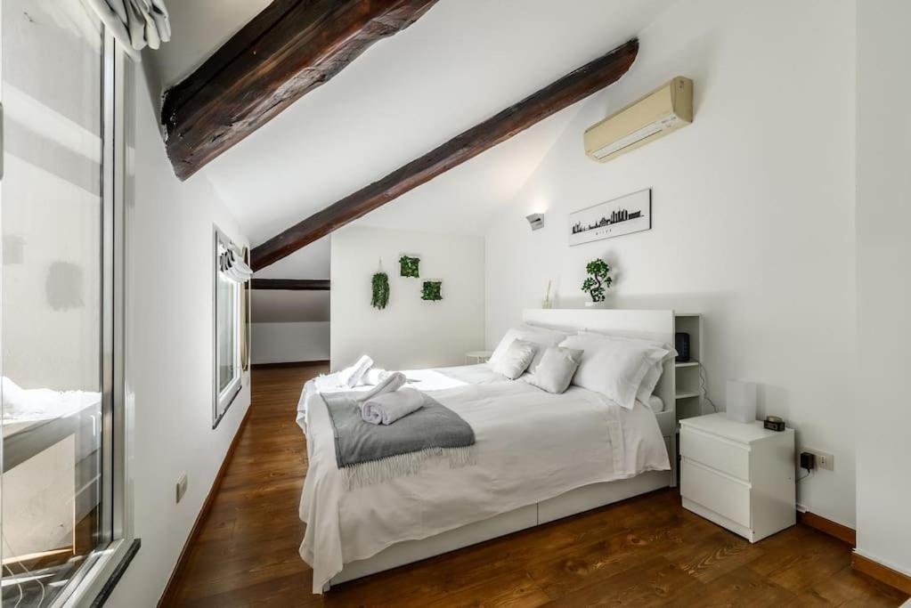 una camera da letto bianca con un letto grande e pavimenti in legno di Buenos Aires' Nest - 10 minutes from Duomo with terrace a Milano