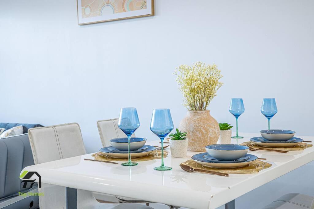 a white table with blue dishes and wine glasses at Entire 3 Bedroom in Bankstown in Bankstown