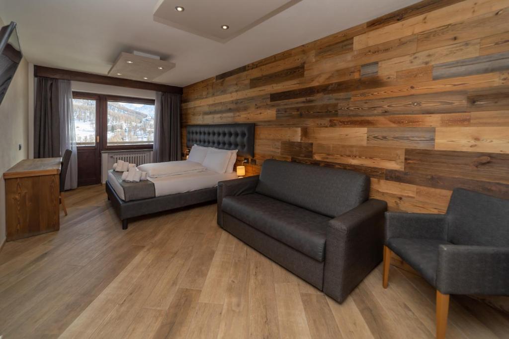 a bedroom with a bed and a couch and a chair at Hotel Gran Roc in Sestriere