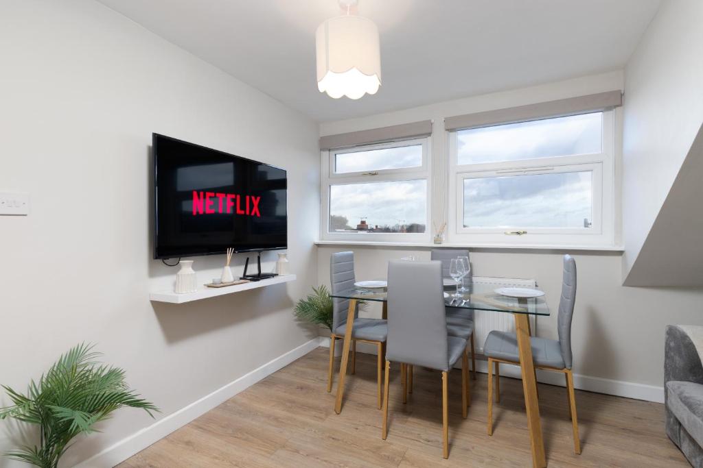 a dining room with a table and chairs and a tv at Cosy Apartment Coventry City Centre in Coventry