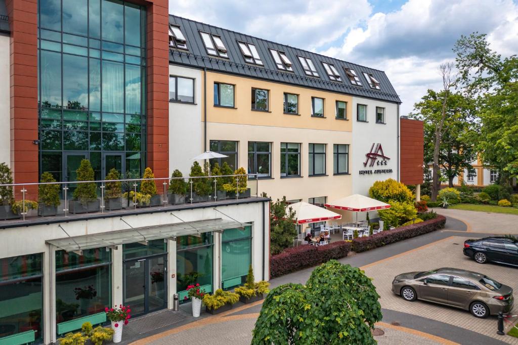 a building with a car parked in front of it at Hotel Austeria Conference & Spa in Ciechocinek