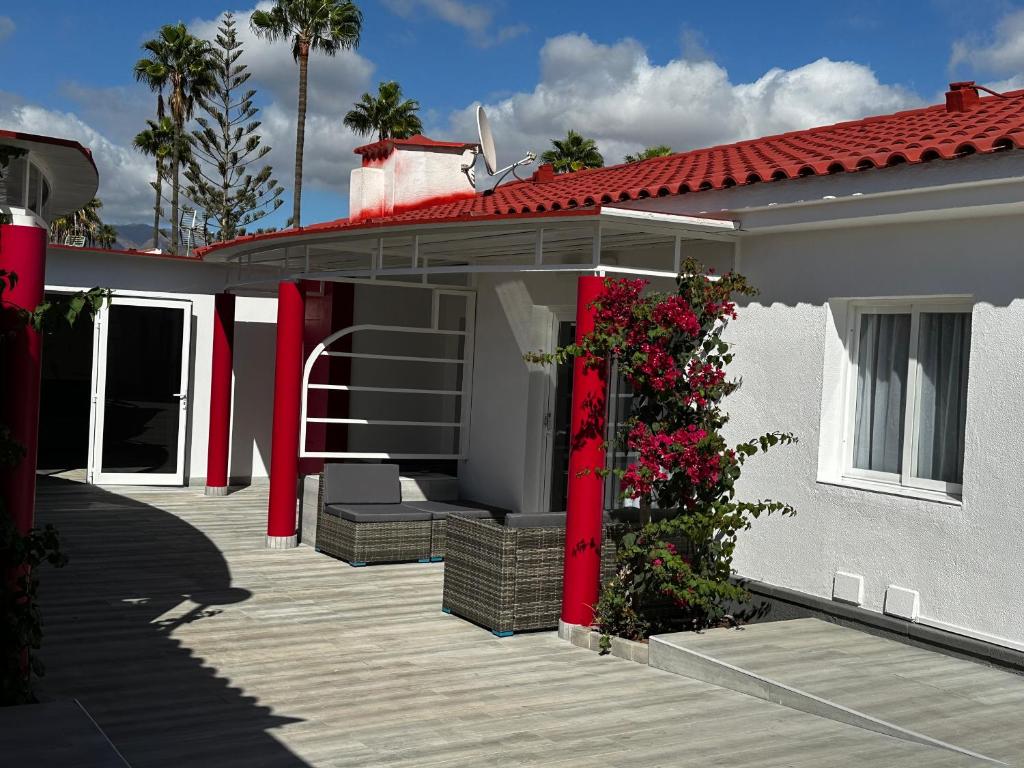 a white house with red doors and a deck at Paradise Resort - FKK Swinger & Nudist Couples Only in Maspalomas