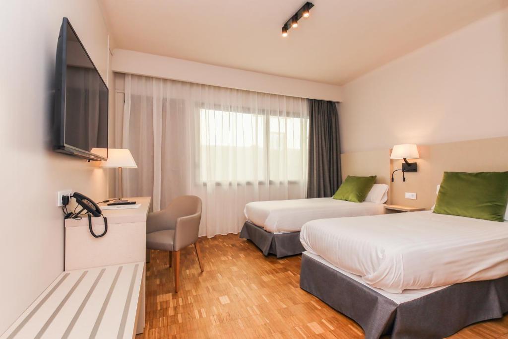 a hotel room with two beds and a flat screen tv at Hotel Lauria in Tarragona
