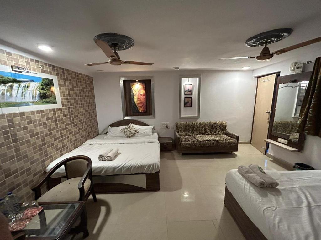 1 dormitorio con 2 camas, silla y sofá en The Peach Tree Rooms, en Mount Abu
