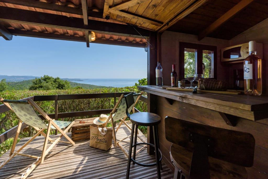 a porch with a bar and chairs and a view at Camping U Pirellu in Porto-Vecchio