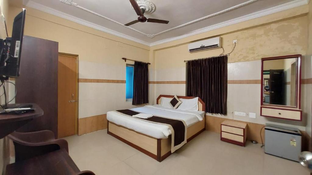 a bedroom with a bed and a desk and a television at Goroomgo Star Inn Puri in Puri