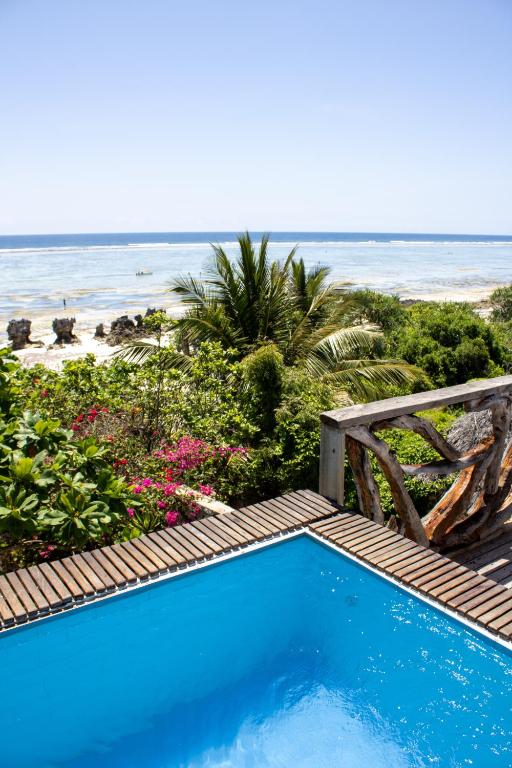 a swimming pool with the beach in the background at Zi Villa Dhow Beach Cottage in Matemwe