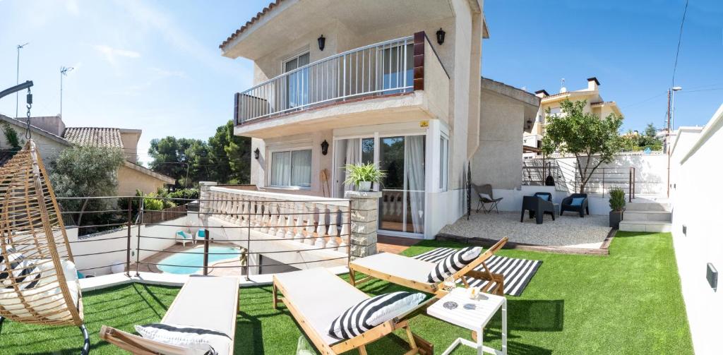 una casa con un cortile con sedie e una piscina di VILLA WINE & BEACH Design and Luxury in Cala Crancs a Salou