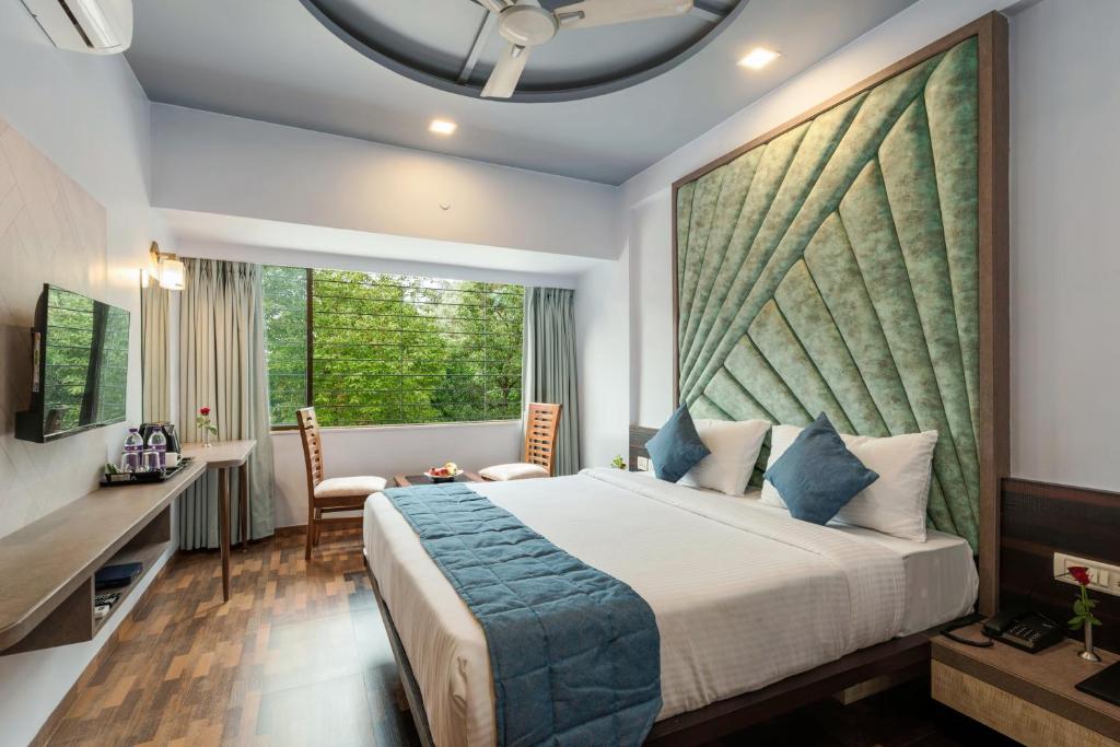 a bedroom with a bed and a desk and a window at Emerald Retreat in Lonavala