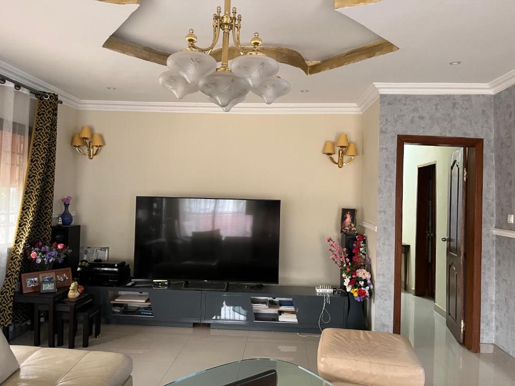 a living room with a large television and a chandelier at Residence ABIS 
