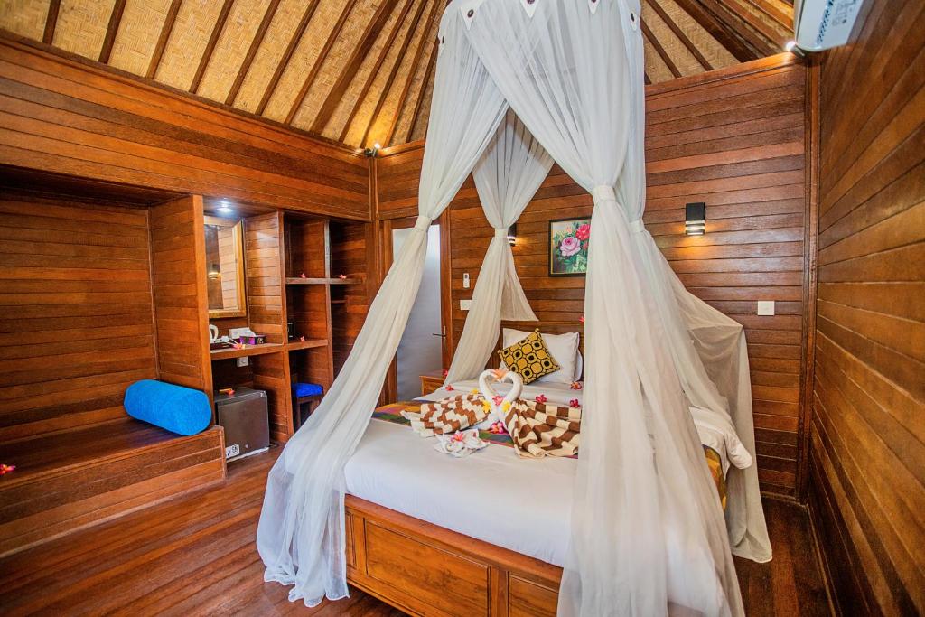 a bedroom with a bed with a mosquito net at Bagus Dream Beach Villa Lembongan in Nusa Lembongan