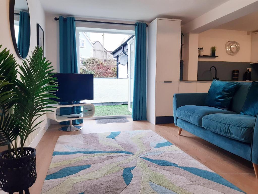 a living room with a blue couch and a large window at No's 2 and 5 Llewelyn Apartments in Llanberis