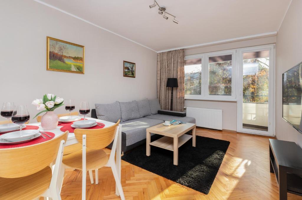 a living room with a table and a couch at Oliwa Forest Apartment with Balcony by Renters in Gdańsk