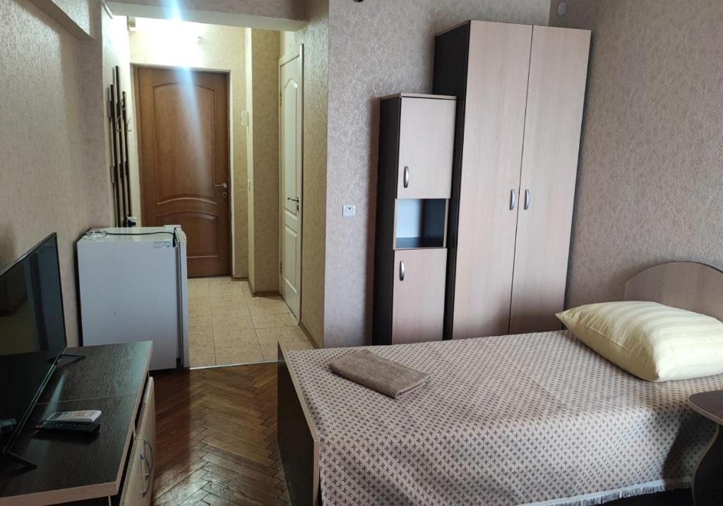 Dormitorio pequeño con cama y nevera en Hotel Prietenia en Bender