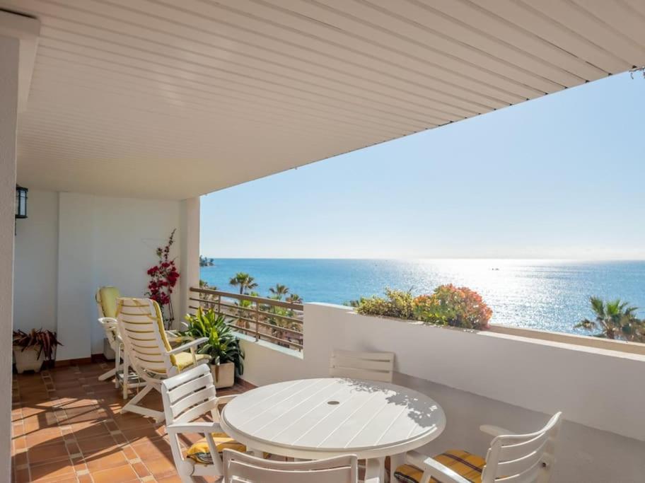 einen Balkon mit einem Tisch, Stühlen und Meerblick in der Unterkunft Gran apartamento primera línea in Estepona