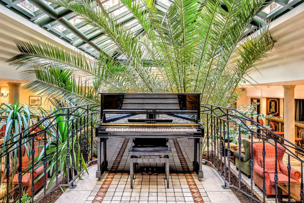 een piano in een kamer met palmbomen bij Villa Beaumarchais in Parijs