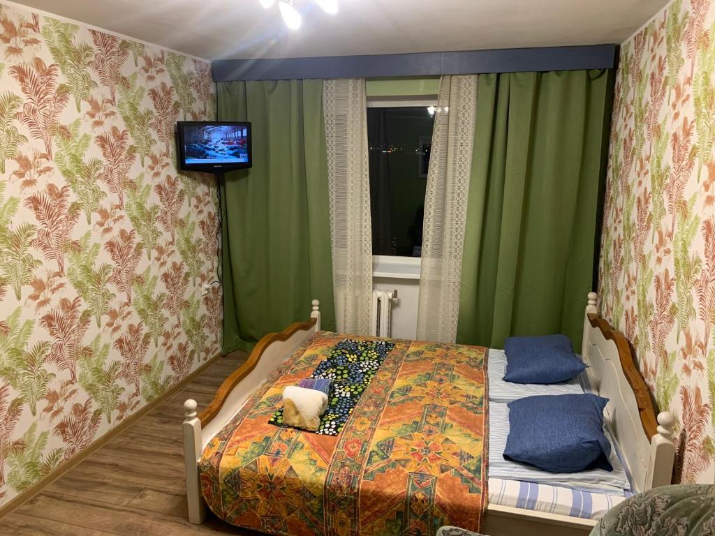 a bedroom with a bed with a tv on the wall at Jalaka, Nice 2-bedroom apartment - 1 big bed - 2 single bed in Tartu