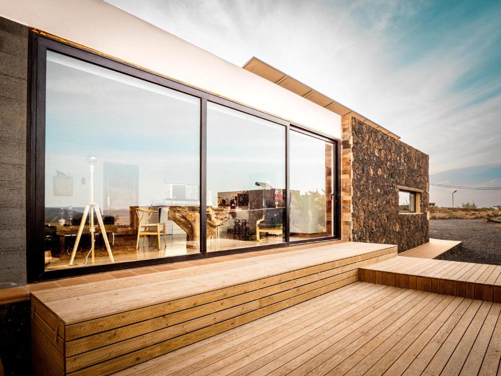 CASA LA BOCAINA - private villa with panorama & ocean view في Villaverde: منزل به نوافذ كبيرة وسطح خشبي