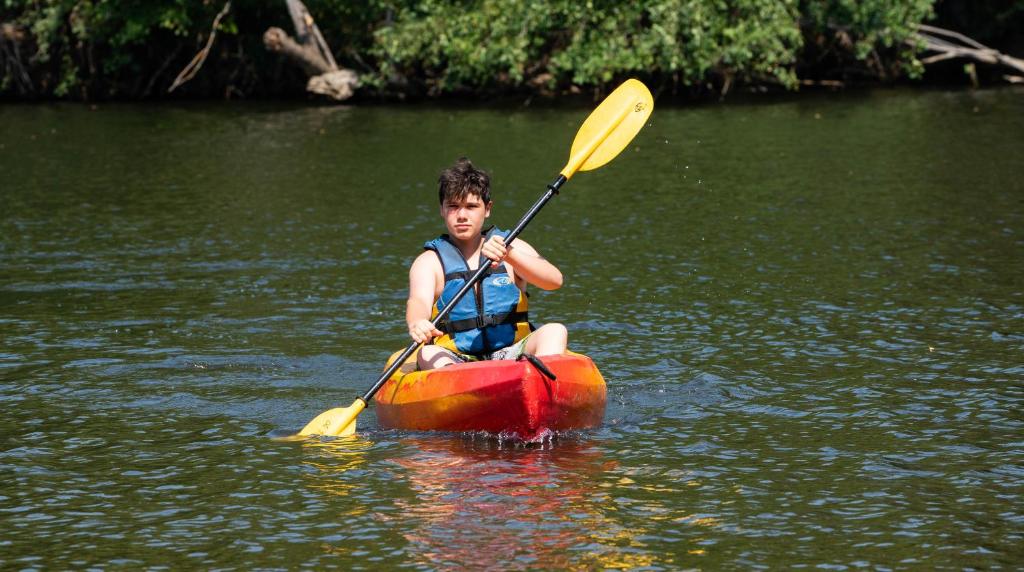 a young boy in a kayak in the water at Camping de la Bageasse in Brioude