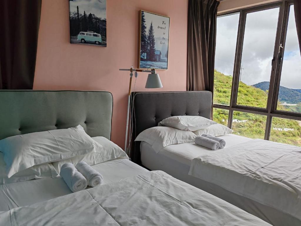 dwa łóżka w pokoju z oknem w obiekcie Kensington Sunrise at Sg Palas,PalasHorizon w mieście Tanah Rata