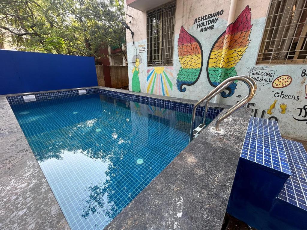 a swimming pool with a mural on the side of a building at Ladakh House- 3 BHK Ladakh themed Villa near Matheran in Neral