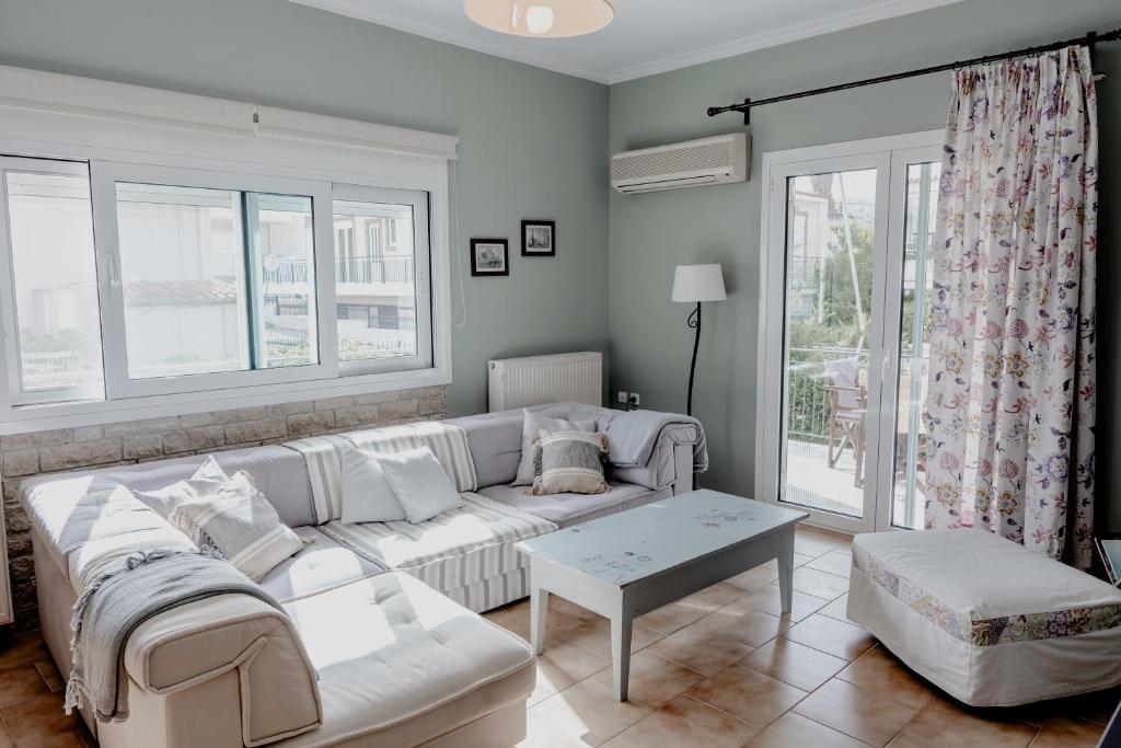 a living room with a white couch and a table at Va Yia/ Spacious guest house in Nafplio