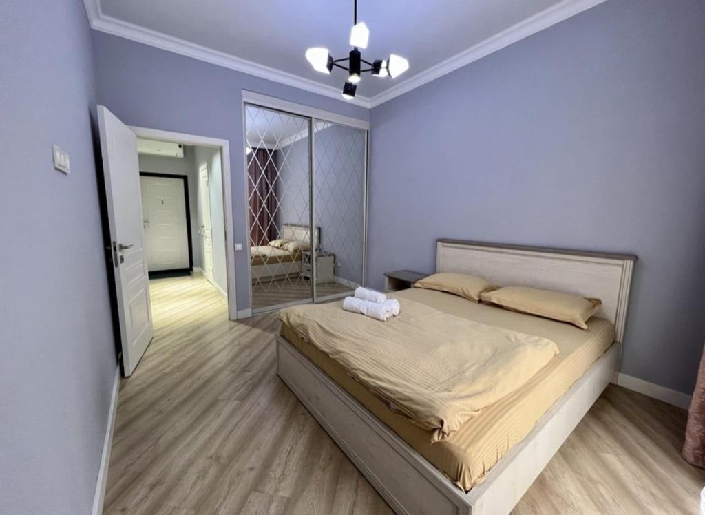 Un dormitorio con una cama grande y un espejo. en Приятные апартаменты в элитном комплексе, en Almaty