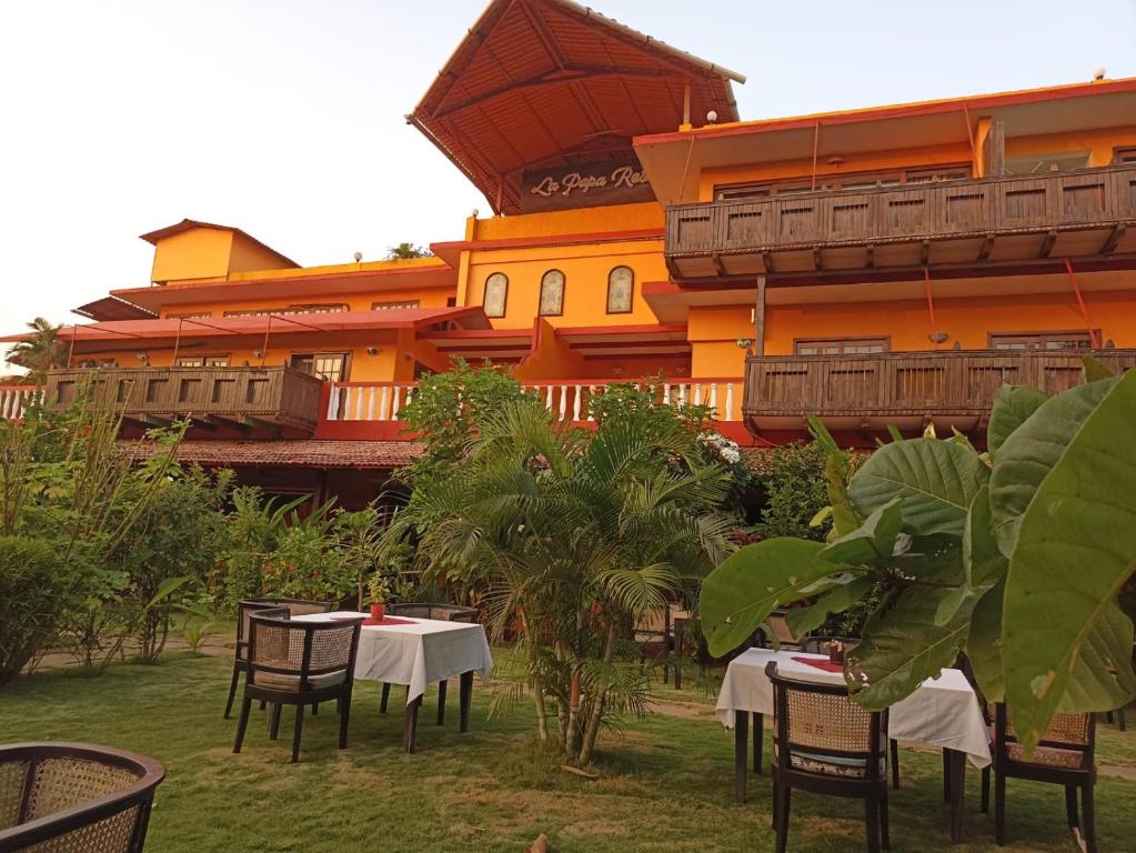 a restaurant with tables and chairs in front of a building at La Papa Resort in Morjim