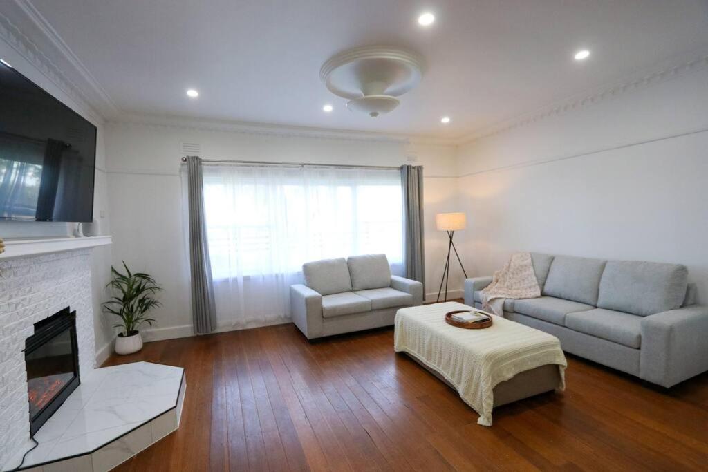 a living room with two couches and a fireplace at Hideaway Homestead in Nagambie