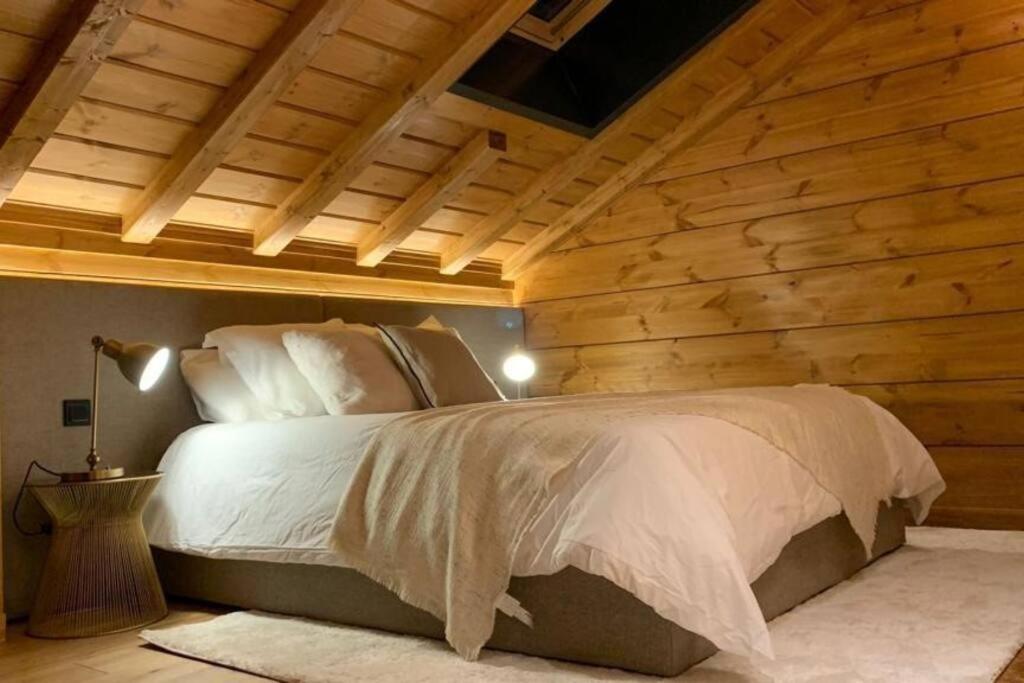 a bedroom with a bed with a wooden wall at Arttysur Lux Village Sierra Nevada Casa 8 Superlujo in Sierra Nevada