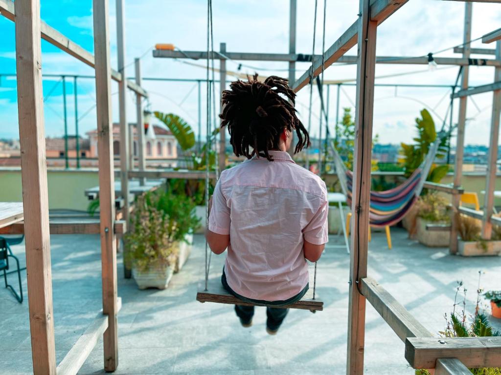 a person sitting on a swing on a roof at Ostello Bello Roma Colosseo in Rome