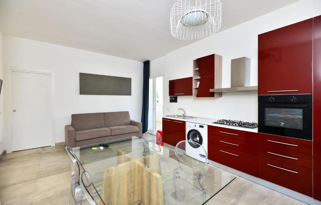 una cocina con armarios rojos y un sofá. en Damavi suite 3, en Torre dell'Orso