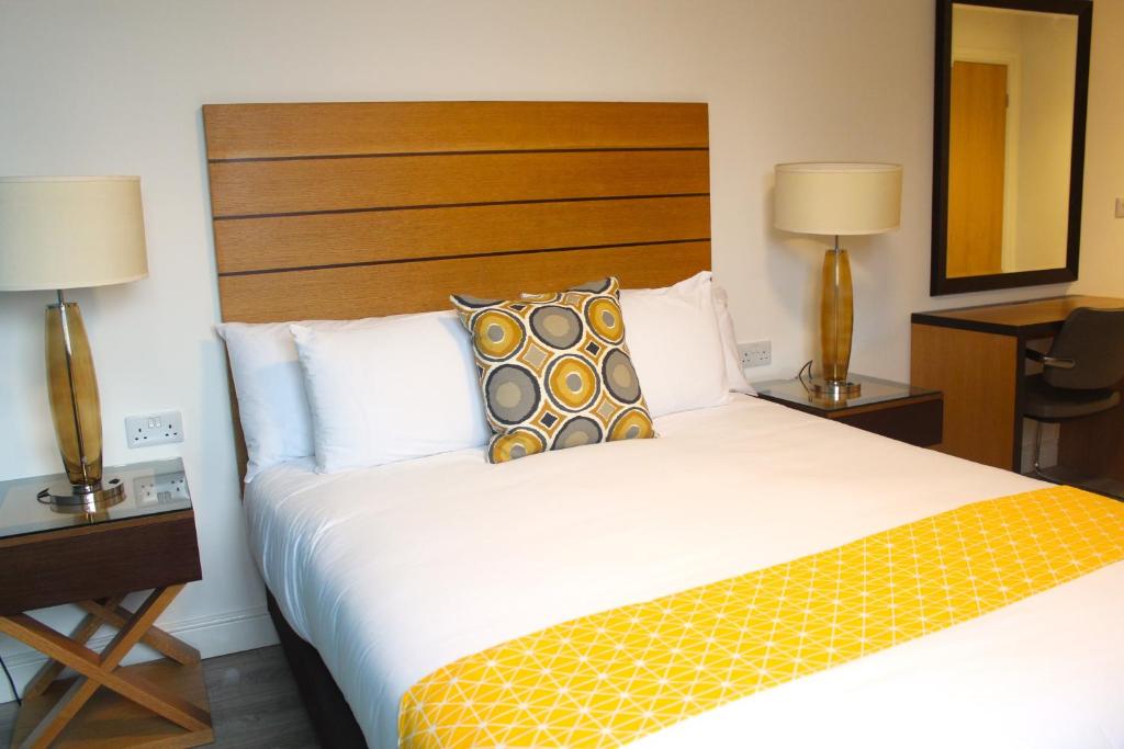 Maze apartments and rooms في هال: سرير في غرفة الفندق مع مصباحين